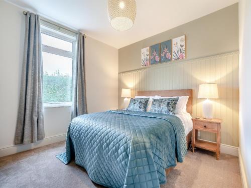 a bedroom with a bed with a blue comforter and a window at Highbury in Rothbury