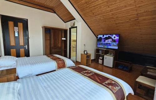 een hotelkamer met 2 bedden en een flatscreen-tv bij Villa Pink House in Da Lat