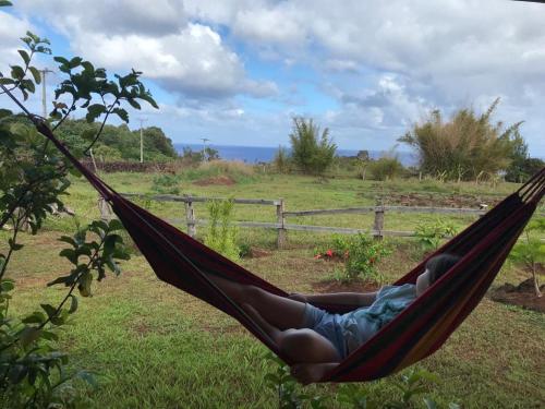 a person sleeping in a hammock in a field at Villa Maori Tea Rapa Nui, Easter Island with ocean view in Hanga Roa