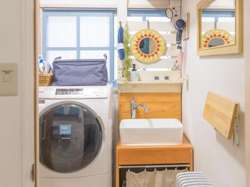 een wasruimte met een wasmachine en een wastafel bij PEDAL TERRACE in Iida