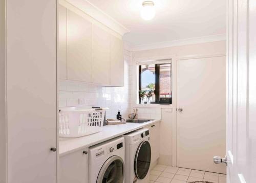 a white kitchen with a washing machine and a sink at Budgaribah in Old Bar
