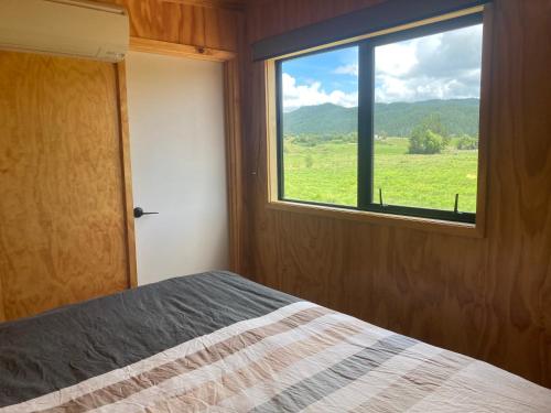 a bedroom with a bed and a window with a view at White Pine Bush Cabins in Otangihaku