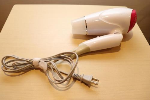 a hair dryer on a wooden table with a cord at YOU STYLE HOTEL MATE 鹿児島 天文館 in Kagoshima