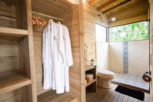 La salle de bains est pourvue de serviettes blanches accrochées à un mur en bois. dans l'établissement Cabañas Refugio Himalaya, à Guatapé