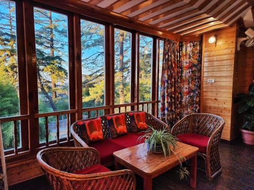 ein Wohnzimmer mit einem Sofa, Stühlen und einem Tisch in der Unterkunft Hotel Pineview Shimla in Shimla
