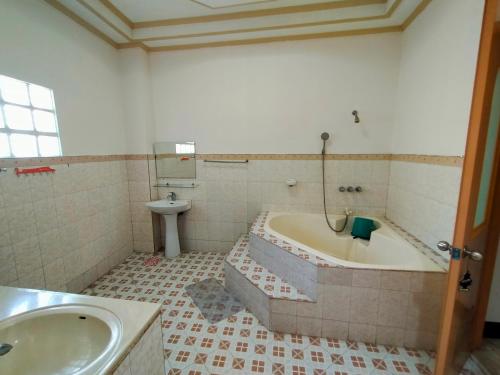 Chelsiefaye Guest House في لواوْغ: حمام مع حوض استحمام ومغسلة