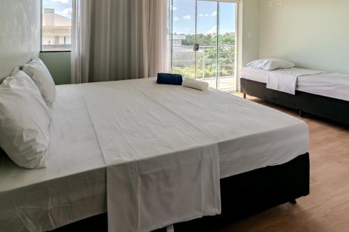 a bedroom with two beds and a large window at Suíte 1 - Pousada Karaiba in Uberlândia
