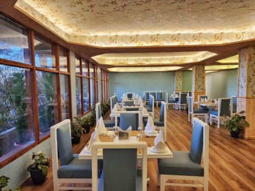 uma sala de jantar com mesas, cadeiras e janelas em Hotel Pineview Shimla em Shimla