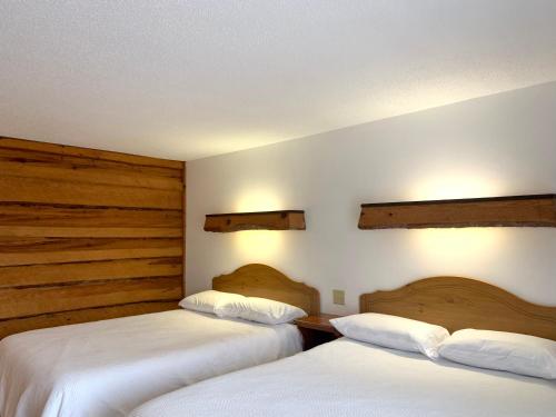 2 camas en una habitación de hotel con sábanas blancas en Bridge Inn Tomahawk -1st Floor, 2 Queen Size Bed, Walkout, River View, en Tomahawk