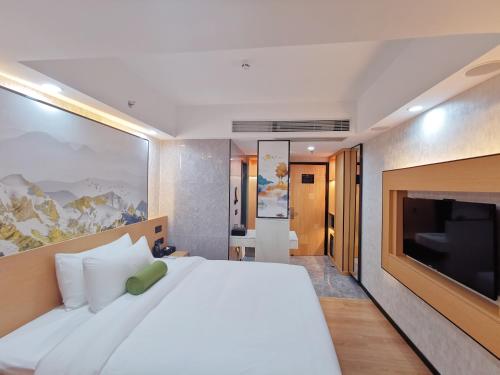 a bedroom with a large white bed and a flat screen tv at Connar Hotel - Shenzhen Futian in Shenzhen