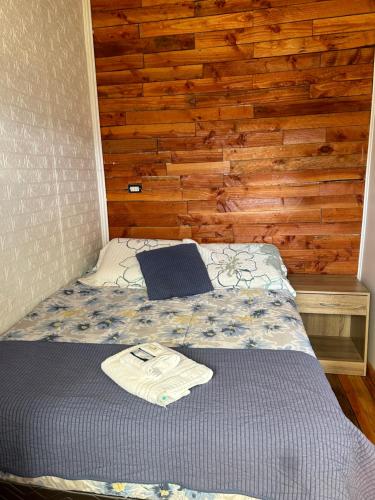 a bed in a room with a wooden wall at Cabañas La Tranquilidad in Purranque
