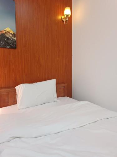 a bedroom with a white bed with a wooden wall at An Homestay - Bar & Motorbike Rental in Cao Bằng