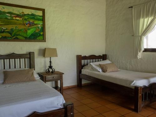 two beds sitting in a room with a window at Finca Hotel Santana in Montenegro