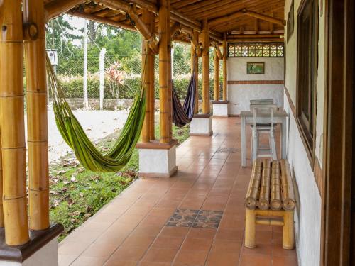 a porch with a hammock and a table and a bench at Finca Hotel Santana in Montenegro