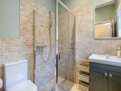 a bathroom with a shower and a toilet and a sink at Peartree Cottage - Uk45496 