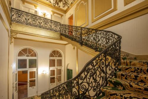 a staircase in a house with a wrought iron railing at Korona Hotel in Nyíregyháza
