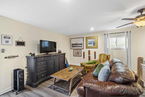 uma sala de estar com um sofá de couro e uma televisão em Mile to Beach! Tiki Master Suite em Oceanside