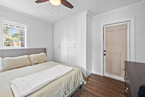 een witte slaapkamer met een bed en een plafondventilator bij Comfy Modern Farmhouse Cottage w/ Private Patio! in Tampa