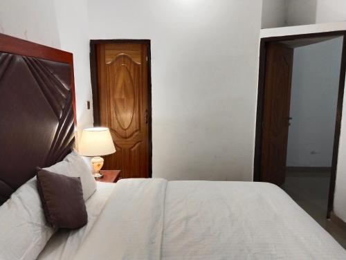 a bedroom with a bed and a lamp and a door at Homewood Suites Family Guest House & Apartments in Lahore