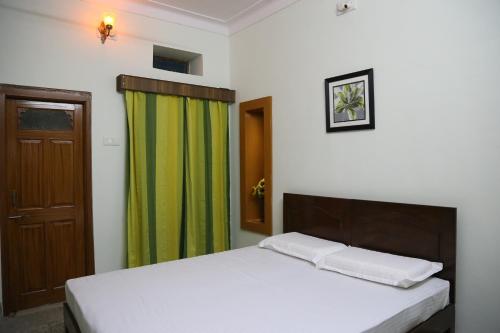a bedroom with a bed and a green curtain at Raaga Home in Udaipur
