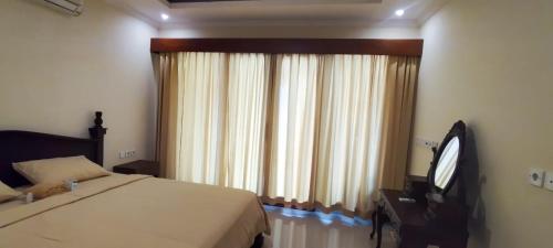 Schlafzimmer mit einem Bett, einem TV und einem Fenster in der Unterkunft Bejae Kummar Suite in Ubud