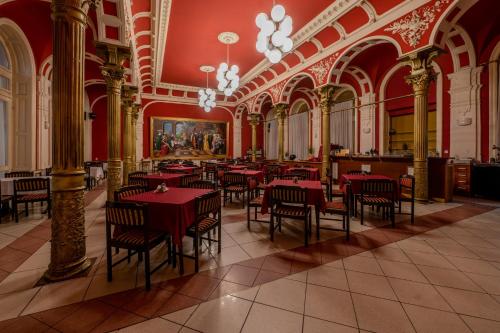 a restaurant with red tables and chairs in a building at Korona Hotel in Nyíregyháza
