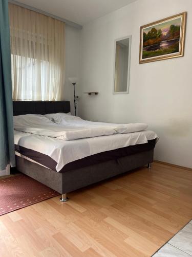 duże łóżko w sypialni z drewnianą podłogą w obiekcie Studio apartman Dora w mieście Vinkovci