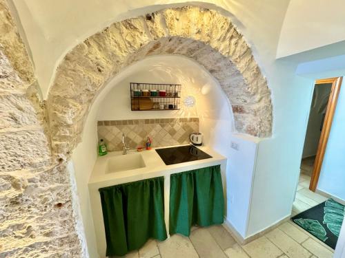 una cucina con lavandino e parete in pietra di Luxury Trulli with Terrace ad Alberobello