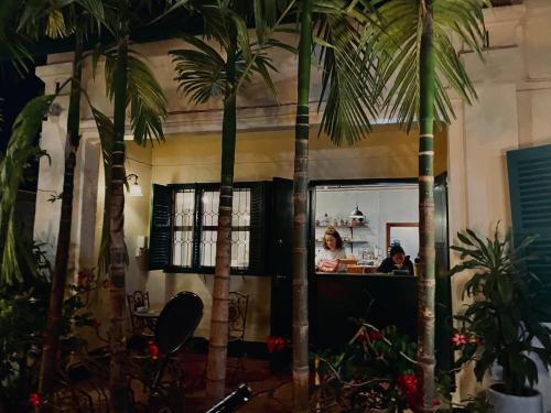 a woman standing at a counter in a restaurant with palm trees at Barn1920s Hostel in Vientiane