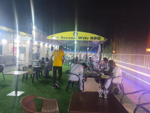 a group of people sitting at tables at a restaurant at Homewood Suites Family Guest House & Apartments in Lahore