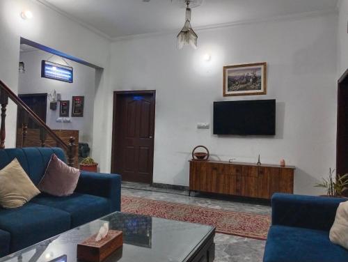a living room with two blue couches and a tv at Homewood Suites Family Guest House & Apartments in Lahore