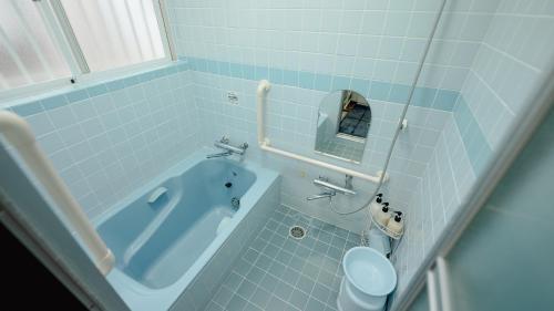 a bathroom with a blue tub and a toilet at AMAMI-Green-Garden in Amami