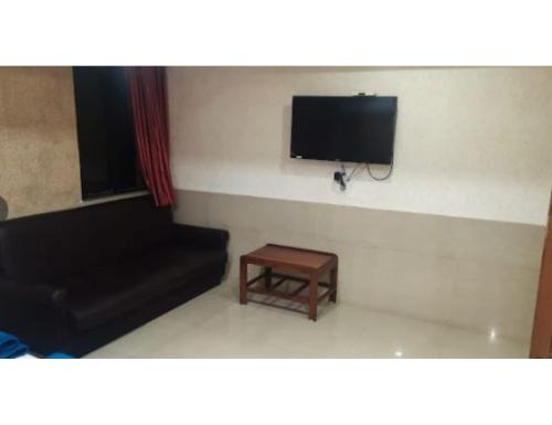 sala de estar con sofá y TV de pantalla plana en Hotel Janki Guest House, Jamnagar, en Jamnagar