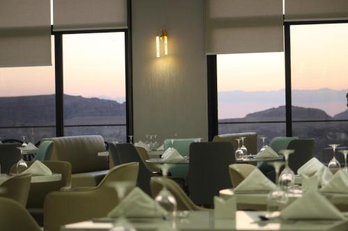 a dining room with tables and chairs and windows at H Luxury Hotel in Wadi Musa