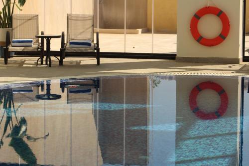 a swimming pool with a red life preserver and two chairs at H Luxury Hotel in Wadi Musa