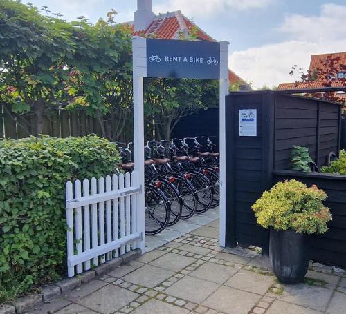 a sign with bikes parked next to a fence at Toftegården Guesthouse - Rooms in Skagen