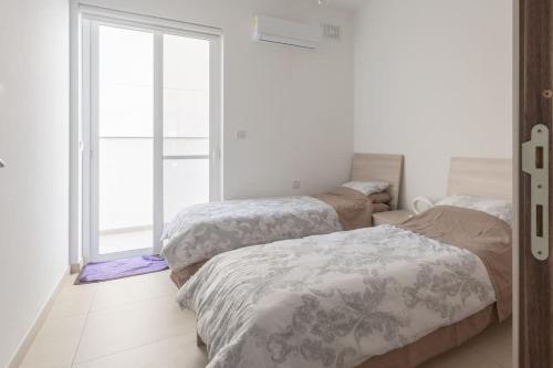 twee bedden in een kamer met een raam bij Full Air-conditioned, 2 Bedroom Apt. in Żejtun