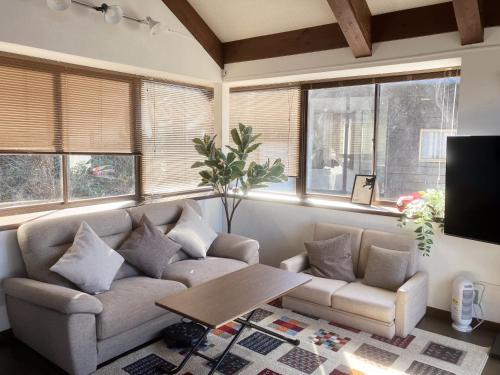 a living room with a couch and a table and windows at 南箱根 熱海 貸切別荘 リゾートハウス トモ in Atami
