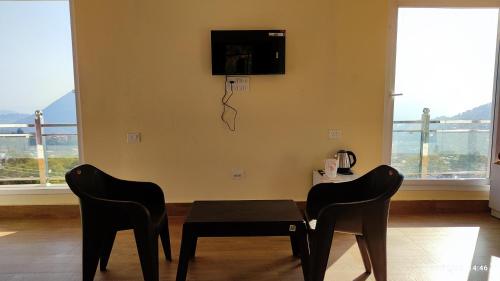 comedor con mesa, 2 sillas y TV en Host Labs Homestay - Premium View - Close to Kaichi Dham, Bhimtal, Sattal, and more, en Bhimtal