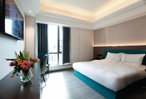 a hotel room with a bed and a vase of flowers at Mei Gang Hotel in Guangzhou