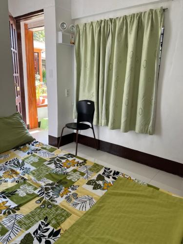 a bedroom with a bed and a chair and a window at Jancas Vacation Home Camiguin Couple Room 2 in Catarman