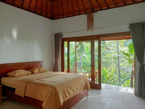 a bedroom with a bed and a large window at Purana Guest House in Tabanan