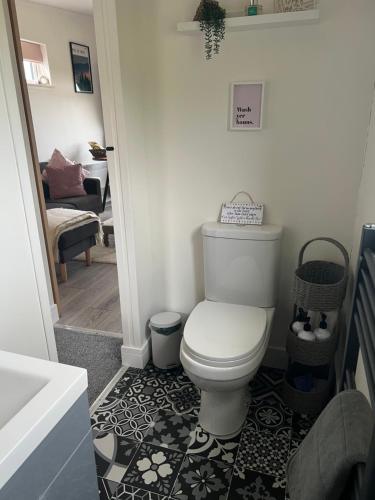 een badkamer met een toilet en een zwart-witte vloer bij Island Coorie in Kilmaluag