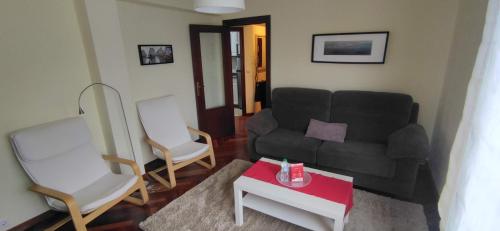 uma sala de estar com um sofá preto e duas cadeiras em Apartamento en Solares em Valdecilla