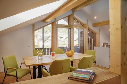 a dining room with a wooden table and green chairs at Fewo Karwendelliebe in Mittenwald