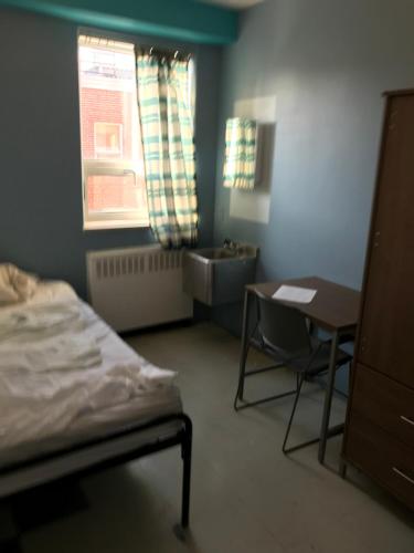 Schlafzimmer mit einem Bett, einem Tisch und einem Fenster in der Unterkunft Sweet Montreal room in Montreal