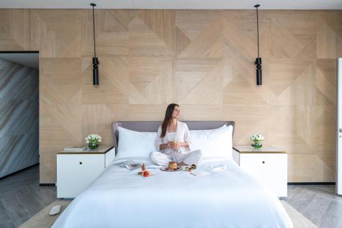 a woman sitting on top of a bed at Rixos Gulf Hotel Doha in Doha