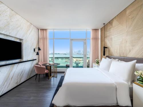 a bedroom with a large white bed and a large window at Rixos Gulf Hotel Doha in Doha