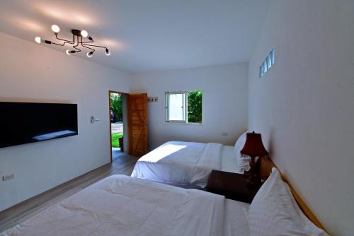 a bedroom with two beds and a flat screen tv at 鳳凰懷舊 in Chenggong