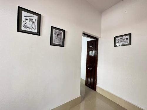 a hallway with three pictures on the wall and a door at Malgudi House - Commandant in Mysore